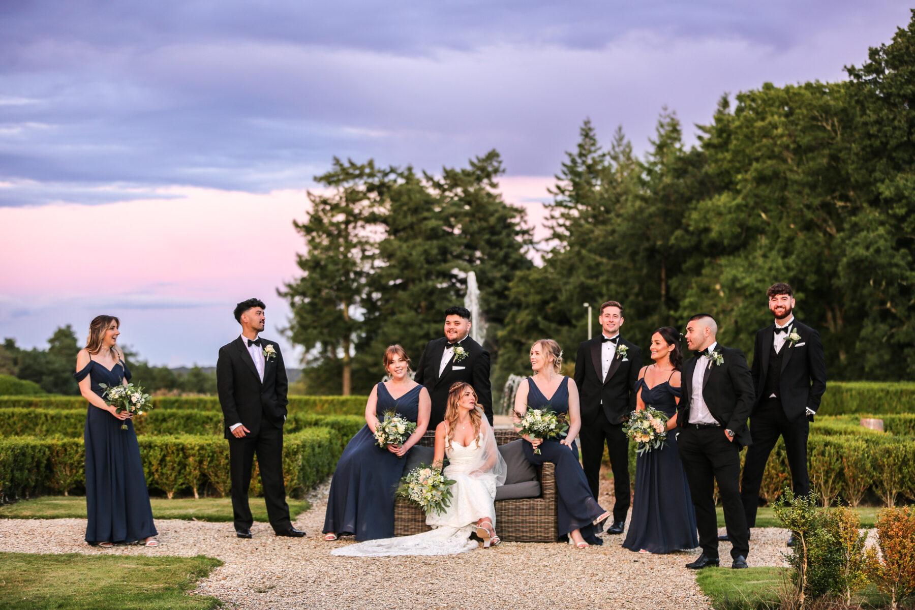 Dorset wedding photographer capturing bride and bridal party in formal gardens at sunset 