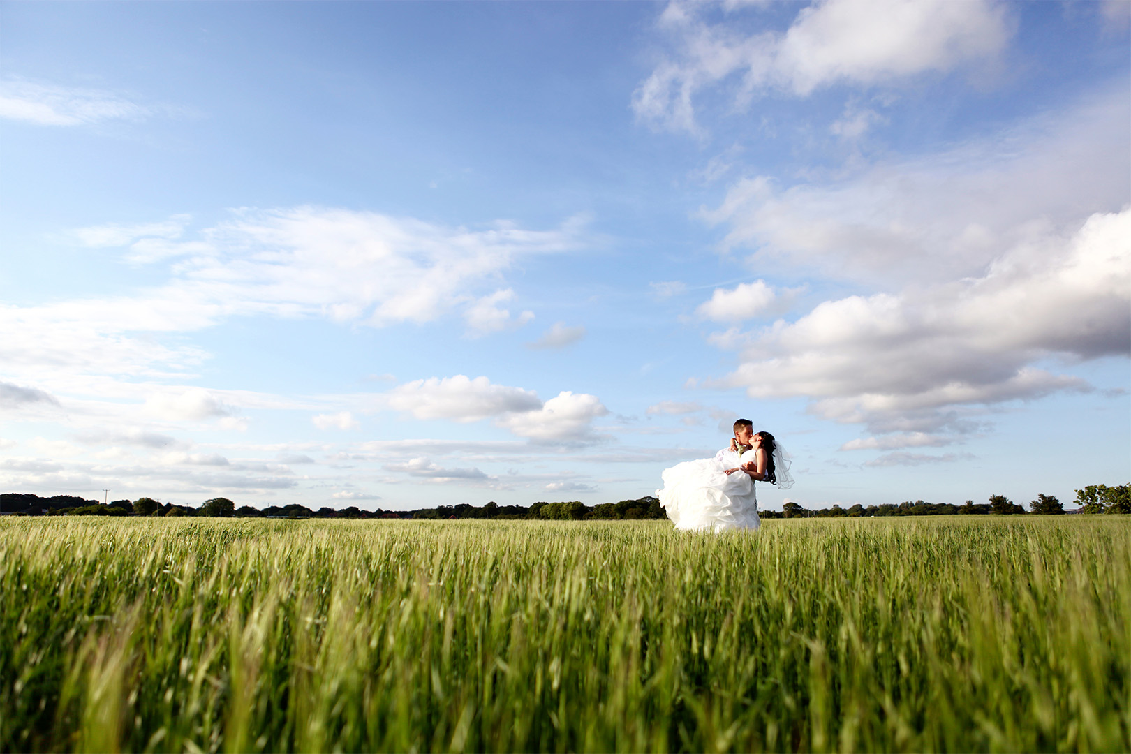 Bride and groom kissing in a Dorset countryside field captured by wedding photography videography Dorset team