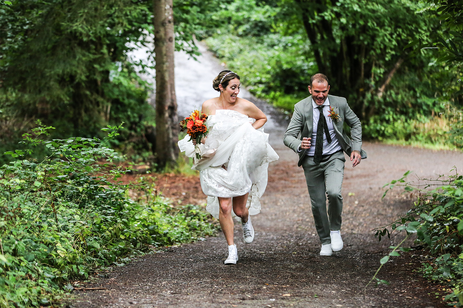 Bride and groom running and laughing along a woodland path in Dorset captured by wedding photography videography Dorset team